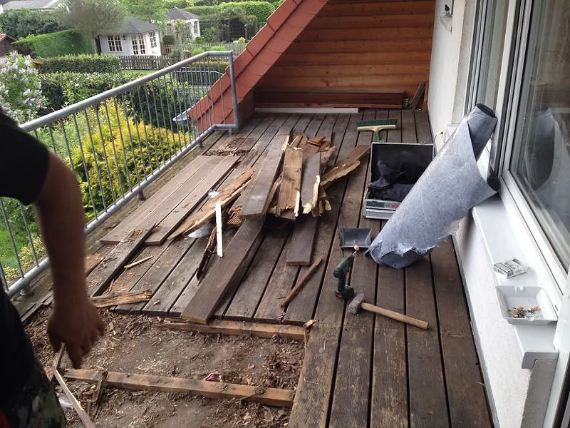 Alter Holzbalkon beim Rückbau, morsche Dielen liegen offen.